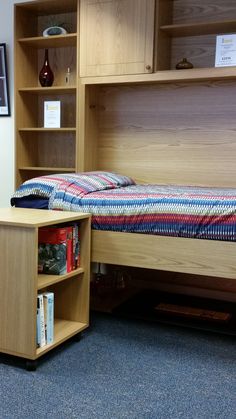 a bed with a book shelf next to it and a desk in front of it