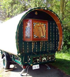 a green and orange covered wagon is parked in the grass