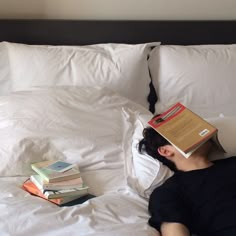 a person laying in bed with books on their head