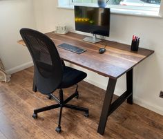 a desk with a computer on it in front of a window