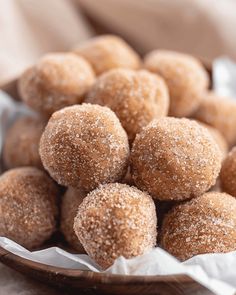 a wooden bowl filled with sugar covered donuts