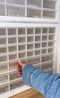 a person's hand is reaching for beads in a drawer