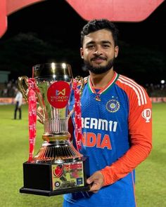 a man holding a trophy on top of a field