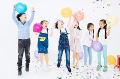 group of children with balloons and confetti in front of white background for photo