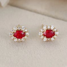 These 18K Yellow Gold Oval Ruby Stud Earrings with a Lab Diamond Halo are the perfect addition to any jewelry collection. Elegant Red Oval Diamond Earrings, Luxury Ruby Earrings With Halo Design, Exquisite Oval Prong-set Earrings, Exquisite Oval Earrings With Prong Setting, Exquisite Oval Prong Set Earrings, Luxury Oval Ruby Earrings, Luxury 14k Gold Oval Earrings, Red Oval Diamond Earrings For Anniversary, Oval Red Diamond Earrings For Anniversary