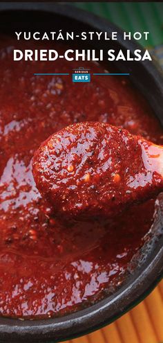 a wooden spoon full of red sauce on top of a pan with the words yucaten - style hot dried - chili salsa