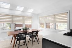 a dining room table with four chairs next to a stove and window covered in blinds