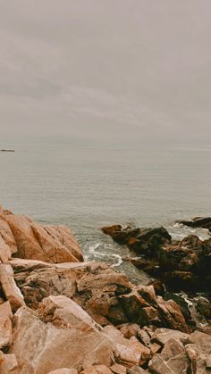 a man standing on top of a rocky beach next to the ocean