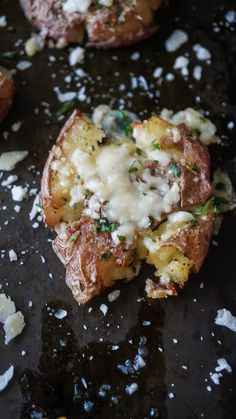 some food that is on top of a black surface with white stuff around it and sprinkled with parmesan cheese