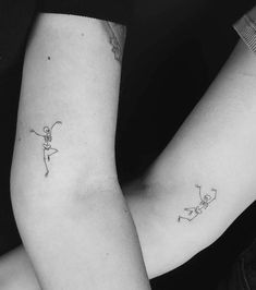 two people with matching tattoos on their arms, one holding the other's arm