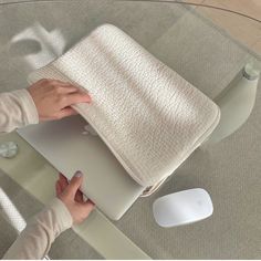 a woman's hand is on top of a laptop computer and she is sitting at a glass table