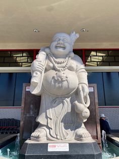 there is a statue in front of a building that has a fountain on the ground