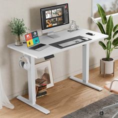 a computer desk with a monitor, keyboard and mouse next to a potted plant