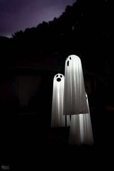 two white ghost statues standing in the dark