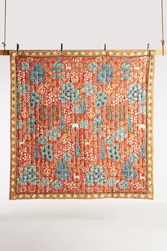 an orange and blue tapestry hanging from a wooden hanger on a white wall,