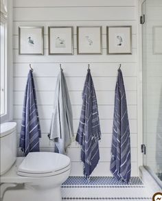 three towels hanging on the wall next to a toilet