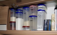 an organized shelf with plastic containers and books