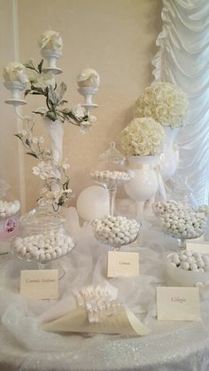 a table topped with lots of white candies and vases filled with flowers next to each other