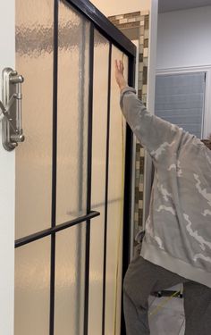 a man standing in front of a glass door holding his hand up to the side