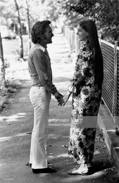 two women standing next to each other on a sidewalk, one holding the hand of another woman