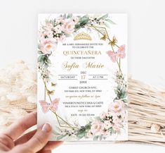 a hand holding up a wedding card with flowers on it and gold foil lettering in the middle