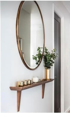 a mirror and some candles on a shelf in a room with a plant next to it