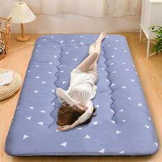 a woman laying on top of a blue mattress