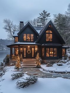 a large house with lots of windows and lights on it's front porch in the snow