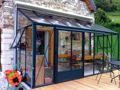 a patio with chairs, tables and a glass door on the side of a stone building