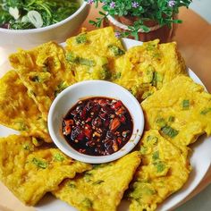 an omelet dish with sauce and vegetables on a plate next to potted plants