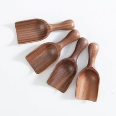 four wooden spoons are lined up on a white surface