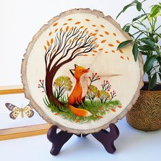 a wooden slice with an image of a fox on it and a butterfly sitting next to it