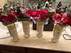 three wine bottles with flowers in them sitting on a counter top next to a sink