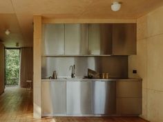 an empty kitchen with stainless steel cabinets and wood flooring is seen in this image