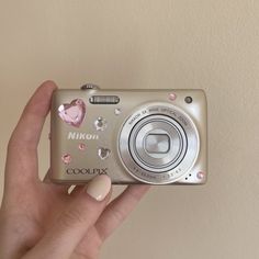 a person holding up a camera with hearts on the front and side of its body