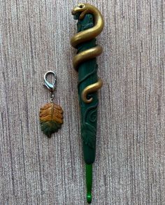 a green pen with a snake on it next to a keychain