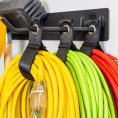 several different colored hoses are hanging on a rack with black hooks and yellow, green, red, and orange cords