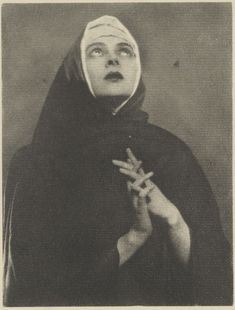 an old black and white photo of a nun holding her hands up in the air