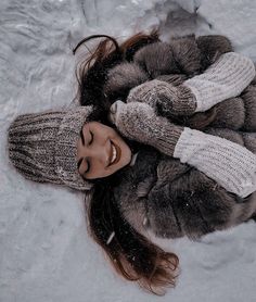 a woman is laying in the snow with her hands on her hips and smiling at the camera