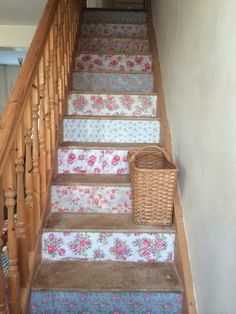 a set of stairs with floral carpet and basket on the bottom one handrails