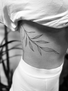 a woman's lower back tattoo with leaves on her stomach and the bottom part of her body