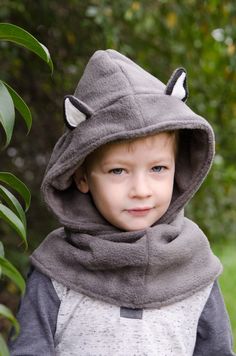 a young boy wearing a hoodie with ears on it's head and eyes closed