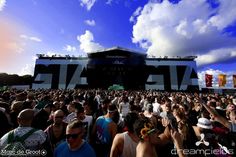 a large group of people standing in front of a stage at a music festival or concert