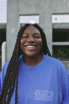 a woman with braids smiling and wearing a blue t - shirt that says stay home