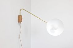 a white wall with a light on it and a lamp hanging from the ceiling next to it