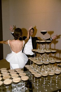 a man and woman standing in front of a table filled with wine glasses