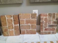 three brick blocks sitting next to each other on top of a tiled floor in front of a wall