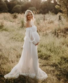 a pregnant woman wearing a white dress standing in a field