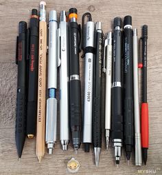 several pens and pencils are lined up on a table with one pen in the middle