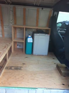 the inside of a van with wood flooring and storage area in it's back